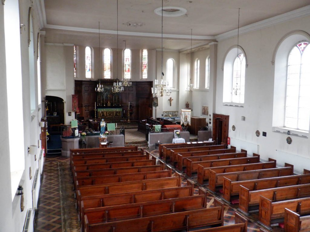 View from the left hand side of the gallery onto the nave with wooden pews, and altar.