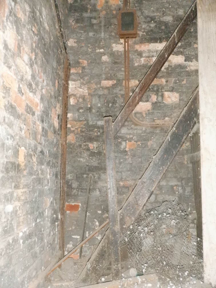 Tucked into the corner of the brick tower walls is the small wooden staircase with a single hand rail