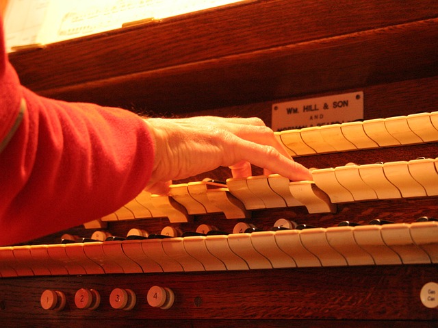 A hand plays an organ keyboard, holding down several keys
